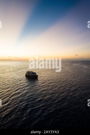 Silhouettes de lever de soleil une plongée à bord d'un bateau à Raja Ampat, Indonésie. Cette région est considérée comme le centre de la biodiversité marine. Banque D'Images