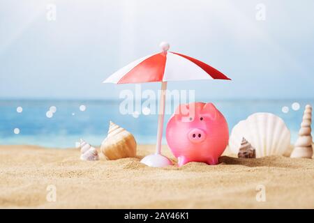 Pink Piggy Bank sous le petit parasol en été à la plage Banque D'Images