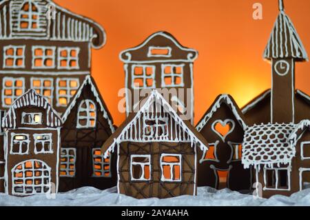 maison a fait traditionnel doux délicieux village de pain d'épices cuit au four en face de fond orange sur le velours blanc de neige comme la décoration de noël pour le Banque D'Images