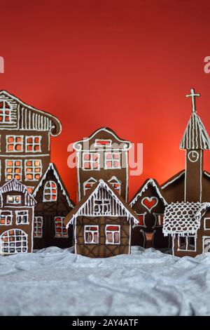 maison a fait traditionnel sucré délicieux village de pain d'épice cuit au four en face de fond rouge sur le velours blanc de neige comme la décoration de noël pour le Banque D'Images