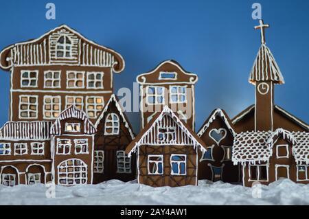 maison a fait traditionnel sucré délicieux village de pain d'épice cuit au four en face de fond bleu sur le velours blanc de neige comme la décoration de noël pour le Banque D'Images