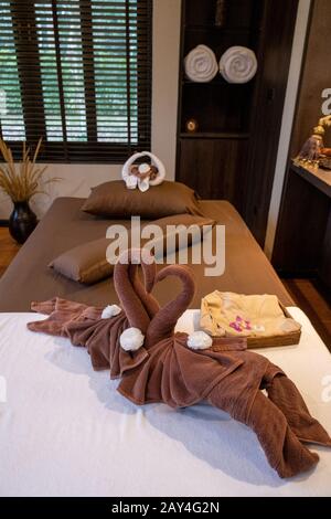 Salle de massage en thaïlande avec fleurs et lit, table de massage dans la chambre Banque D'Images