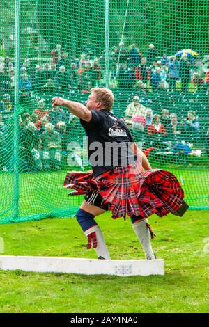 Port de Tartan a Kilted Competitor, mettant la pierre, aux Jeux écossais des Highlands de Braemar, Écosse, Royaume-Uni  des jets lourds Banque D'Images