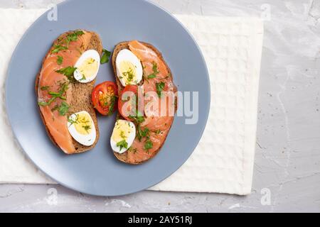 Sandwich au saumon frais avec œufs de caille sur une plaque de gros plan, vue de dessus Banque D'Images