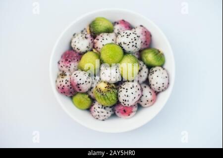 Délicieux dessert aux fruits. Des boules de kiwi et de fruits du Dragon dans un bol isolé sur fond blanc. Salade de fruits exotiques. Concept de sculpture. Pitahaya mûr sous forme de Banque D'Images
