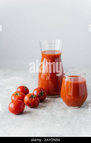 Tomates rouges fraîches mûres à proximité de deux verres de jus de tomate savoureux cousue, sur fond blanc. Ingrédients. Légumes sains Banque D'Images