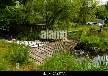 Passerelle en bois et en fer sur un cours d'eau dans un pays paysage. Banque D'Images