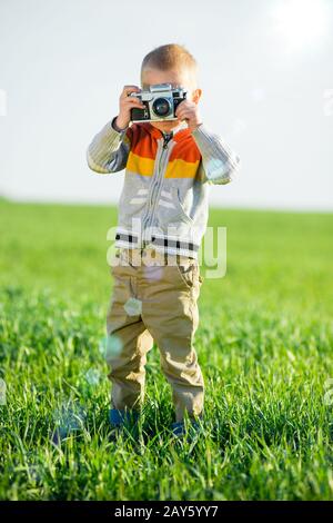 Petit garçon avec un ancien appareil photo shooting en extérieur. Banque D'Images