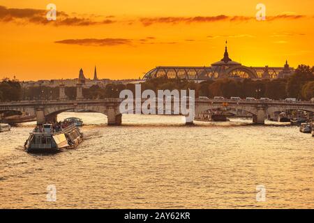 Vue sur le coucher du soleil Sur les ponts de Paris, le Grand Palais et le bateau de croisière sur la Seine Banque D'Images