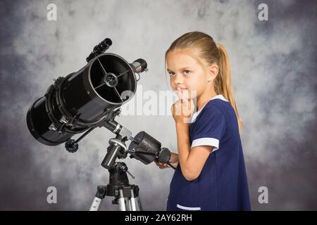 Fille de 7 ans regarde le ciel tout en se tenant au télescope Banque D'Images