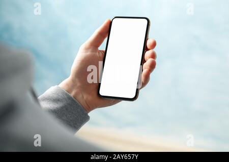 Homme tenant le téléphone avec un écran vide sur fond bleu Banque D'Images