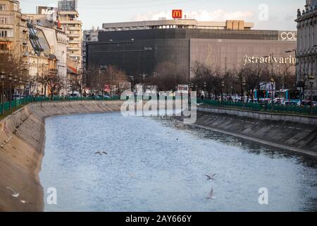 Bucarest, Roumanie - 12 février 2020: Rivière Dambovita avec place Unirii (Piata Unirii) en arrière-plan, à Bucarest. Banque D'Images