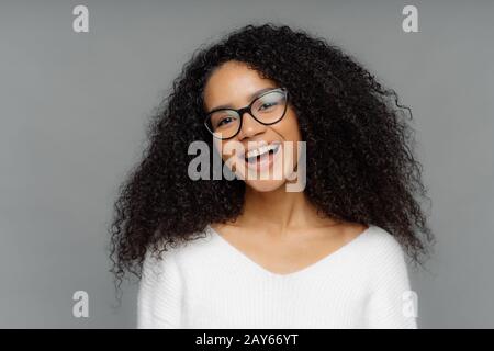 Une femme ébridée et insouciante, surplaisante et sombre, riant heureusement, étant dans un esprit élevé, tisse la tête, a des cheveux maudit, porte un cavalier blanc, entend quelque chose de drôle Banque D'Images