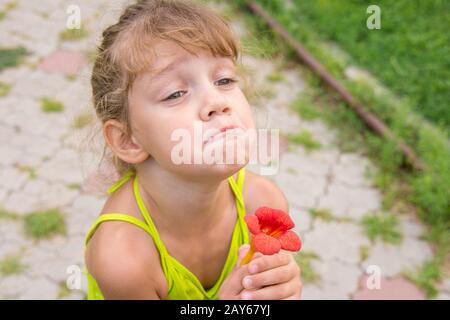 Funny Girl avec une fleur dans sa main fit une grimace à la mendicité Banque D'Images