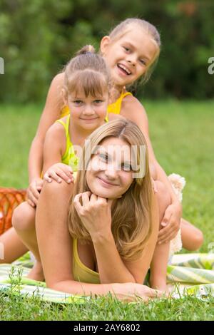 Deux filles sont assises sur la jeune mère, qui est allongé sur l'herbe verte Banque D'Images