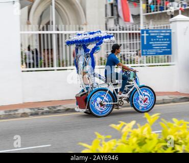 Chauffeur de trishaw devant l'église St. Francis Xavier à Melacca, en Malaisie. A doit monter à Melacca. Banque D'Images