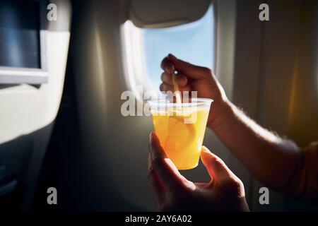 Dring pendant le vol. Homme tenant un cocktail contre la fenêtre d'avion. Banque D'Images