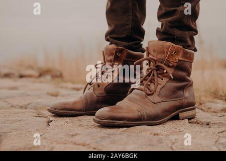 Image des jambes de la mans dans les bottes anciennes. Concept de vente de chaussures. Heure d'automne. Vue horizontale. Prise de vue en extérieur. Chaussures Banque D'Images