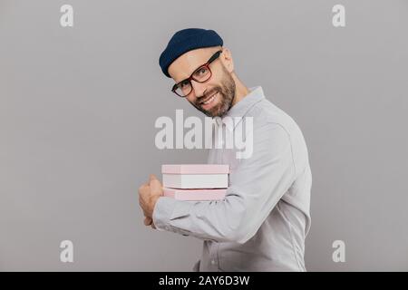 Sourire joyeux barbu avec des professionnels d'expression, de soies, de sombre porte une chemise blanche et des lunettes, porte présente, se dresse en travers en modèles, l'appareil photo Banque D'Images
