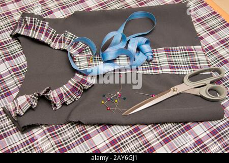 Vue de dessus de l'enfant robe de l'école de billettes allongé sur la table avec accessoires de couture Banque D'Images