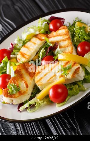 Salade méditerranéenne au fromage hallumi grillé avec tomates, poivrons et laitue qui se ferme sur la plaque de la table. Verticale Banque D'Images