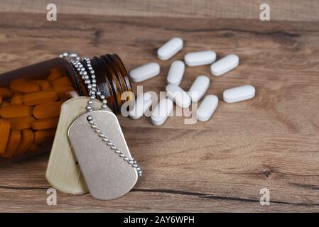 Concept d'abus de drogues militaires. Gros plan d'une bouteille à pilule avec un jeu d'étiquettes de chien drapées sur la bouteille. Banque D'Images