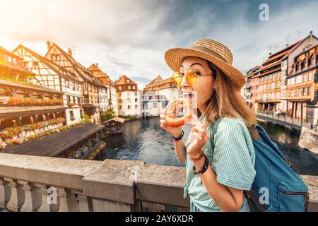 Bonne fille asiatique touriste manger délicieux bretzel pendant son voyage en Europe. Tourisme et concept alimentaire Banque D'Images