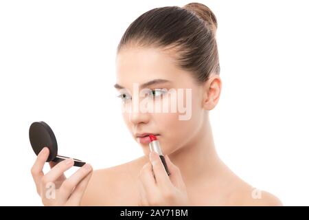 Jeune femme brune avec un visage propre appliquer le rouge à lèvres à l'aide d'un miroir. Isolé sur fond blanc. Banque D'Images