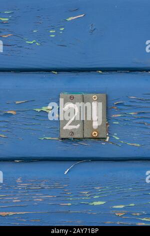 le numéro vingt-et-un ou 21 à la porte d'une cabane chic de plage avec des peintures texturales bleues écaillées. Banque D'Images