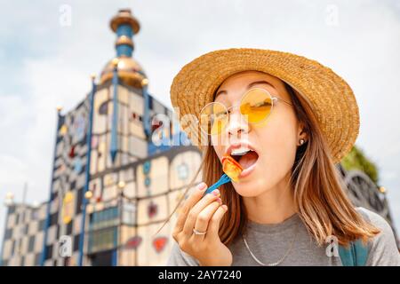 Une heureuse femme asiatique dégustant de délicieuses saucisses autrichiennes à Vienne Banque D'Images