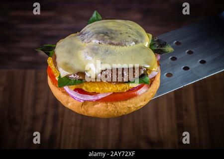 Hamburger végétarien avec fromage, orange, feuilles de basilic, champignons shiitake et oignon violet sur table en bois et fond rustique Banque D'Images