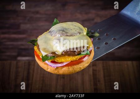 Hamburger végétarien avec fromage, orange, feuilles de basilic, champignons shiitake et oignon violet sur table en bois et fond rustique Banque D'Images