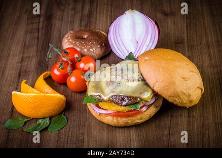 Hamburger végétarien avec fromage, orange, feuilles de basilic, champignons shiitake et oignon violet sur table en bois et fond rustique Banque D'Images