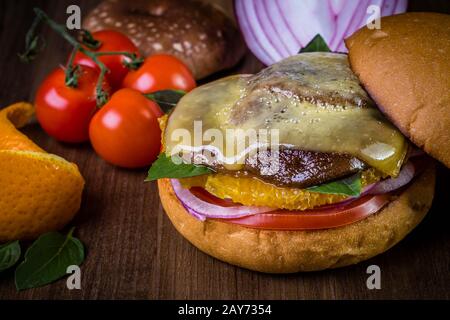 Hamburger végétarien avec fromage, orange, feuilles de basilic, champignons shiitake et oignon violet sur table en bois et fond rustique Banque D'Images