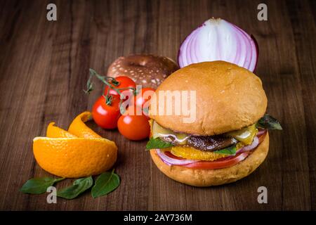 Hamburger végétarien avec fromage, orange, feuilles de basilic, champignons shiitake et oignon violet sur table en bois et fond rustique Banque D'Images