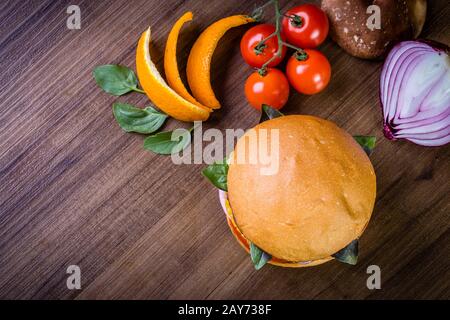 Hamburger végétarien avec fromage, orange, feuilles de basilic, champignons shiitake et oignon violet sur table en bois et fond rustique Banque D'Images