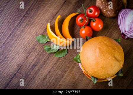 Hamburger végétarien avec fromage, orange, feuilles de basilic, champignons shiitake et oignon violet sur table en bois et fond rustique Banque D'Images