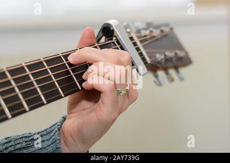 Personne joue de la guitare avec capo et main captivante - vue de détail Banque D'Images