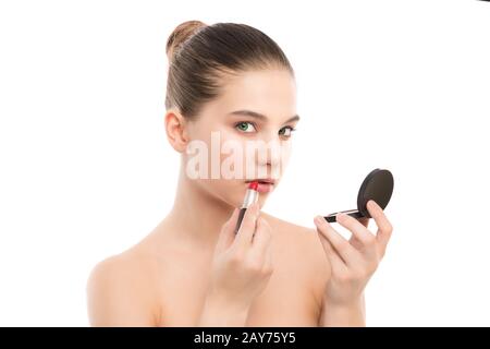 Jeune femme brune avec un visage propre appliquer le rouge à lèvres à l'aide d'un miroir. Isolé sur fond blanc. Banque D'Images