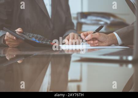 Deux femmes agréés contrôle un état financier ou un dénombrement à la calculatrice pour le revenu d'impôt, les mains de près. Inspecteur de l'Internal Revenue Service Banque D'Images