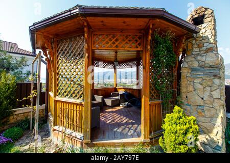 Un belvédère en bois avec un poêle à barbecue en pierre dans l'arrière-cour du cottage. Belvédère à côté de la clôture à l'angle de la cour. Il y a une pelouse verte Banque D'Images