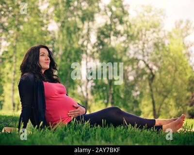 Belle femme enceinte se reposant dans le parc Banque D'Images