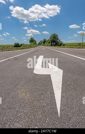 Route avec flèche directionnelle contre un ciel bleu Banque D'Images