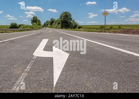 Route avec flèche directionnelle contre un ciel bleu Banque D'Images