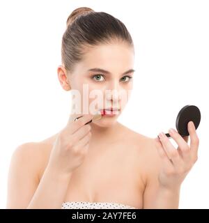 Jeune femme brune avec un visage propre appliquer le rouge à lèvres à l'aide d'un miroir. Isolé sur fond blanc. Banque D'Images