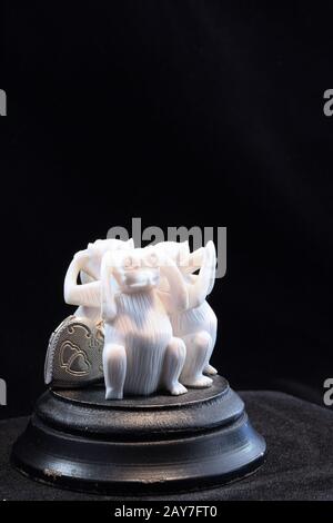 Vous avez sculpté des singes sur une base de bois noir disposés en cercle, couvrant les yeux, les oreilles et la bouche. Petit coeur doré équilibré à gauche de la base, fond noir Banque D'Images