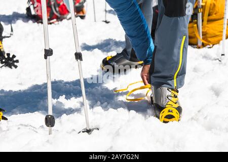 Un jeune randonneur de type habille des Crampons d'escalade sur des chaussures d'alpinisme Pour se promener à travers le glacier Banque D'Images