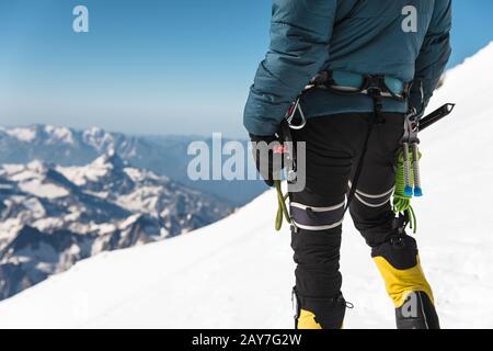 Gros plan UN jeune grimpeur de type tient dans sa main une glace debout sur un sommet haut dans les montagnes. Concept de sport extrême Banque D'Images