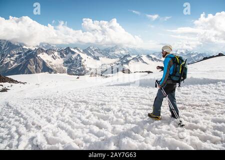 Le voyageur fatigué descend du sommet enneigé sur le fond des montagnes enneigées Banque D'Images