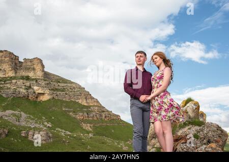 Couple Jeune gars avec une fille tenant les mains debout et regardant loin dans l'arrière-plan d'un beau paysage de roches et de clo Banque D'Images